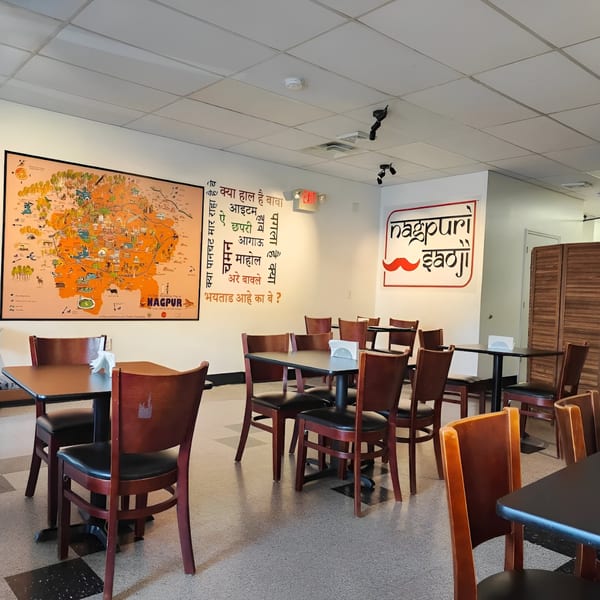 Empty dining room of Nagpuri Saoji with tables, chairs, and a large map of Nagpur on the wall.